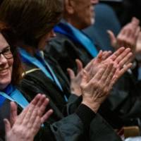 Faculty smile and applaud in the audience